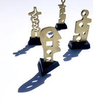 Load image into Gallery viewer, Assorted hammered deep golden brass and steel small sculptures of primitive and modern looking people and parts with black triangle base.