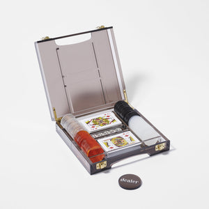 Smoky acrylic poker set with orange, white, and black chips ,clear white dice, and two decks of playing cards. Grey smoke acrylic case with gold framed edges and latches.